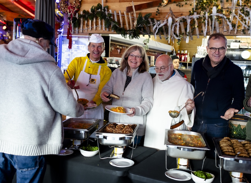 Gäste der Armenküche genießen festliches Mittagessen in der Füchschen Alm