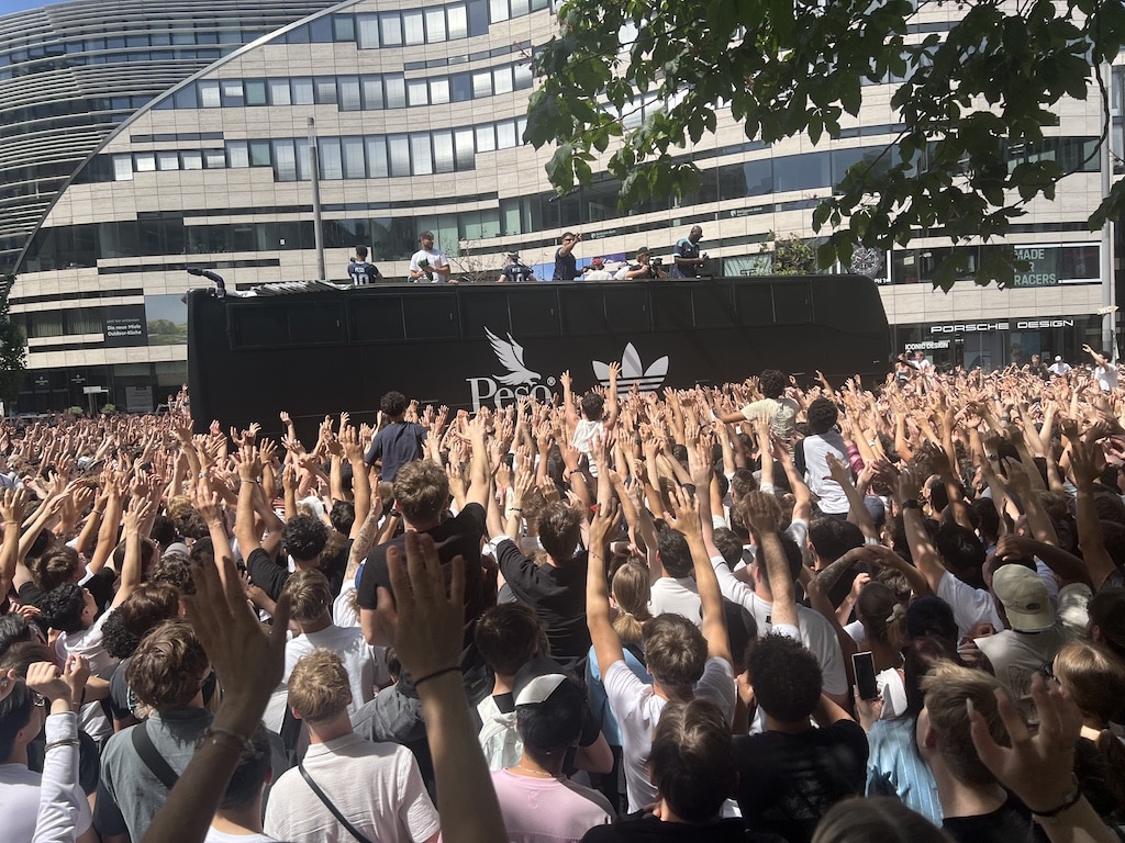 Hunderte Hände recken sich in die Höhe – auf dem Schadowplatz drängten sich am Sonntag bis zu 2000 Menschen um den schwarzen Peso-Adidas-Bus, von dem aus die limitierten Jubiläums-Shirts in die Menge geworfen wurden. © Lokalbüro