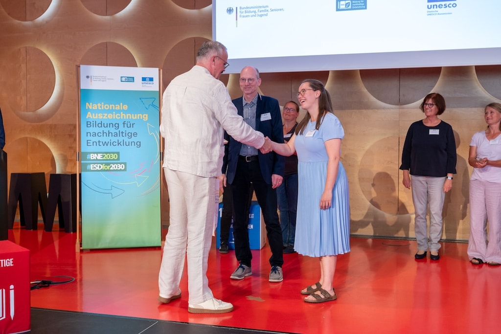 Dr. Elmar Finke (M.) und Melina Lohkamp (r.) nahmen die Auszeichnung durch Bernd Schwarz, Leiter des Referats „Bildung in Regionen, Bildung für nachhaltige Entwicklung“ im BMBSFJ, für den Aquazoo entgegen. © Deutsche UNESCO Kommission/Martin Stollberg