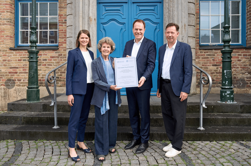 Oberbürgermeister Dr. Stephan Keller (2.v.r.)nahm am Donnerstag, 9. Juli 2026, das offizielle Beitragszertifikat im Netzwerk "Age-friendly Cities and Communities" entgegen. Überreicht wurde es von Dr. Heidrun Mollenkopf (2.v.l.), Vorsitzende von AGE Platform Europe und Vorstandsmitglied der Bundesarbeitsgemeinschaft der Seniorenorganisationen (BAGSO), sowie Ina Voelcker, Leiterin der Geschäftsstelle Internationale Altenpolitik der BAGSO. Mit dabei: Stadtdirektor Burkhard Hintzsche. © Landeshauptstadt